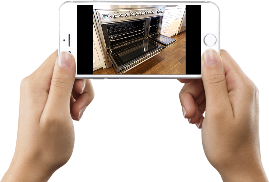 Hands holding a phone with a photo of the same range with both oven doors open